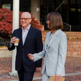 Two Ferguson Wellman employees walking outside with coffee and documents in hand