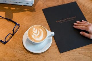 A portfolio with the Ferguson Wellman logo embossed, next to a latte